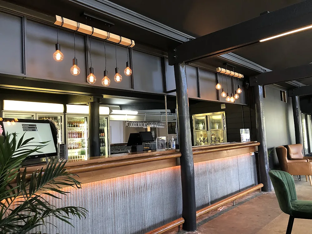 A hospitality bar with pendant lights and LED strip lighting under the counter