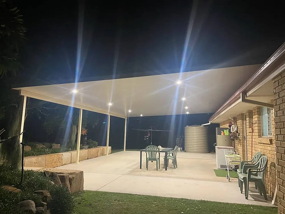 A large patio at night lit by bright downlights under a new roof
